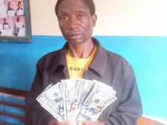 The image shows a man with fake US dollars. The man has been arrested in Malawi